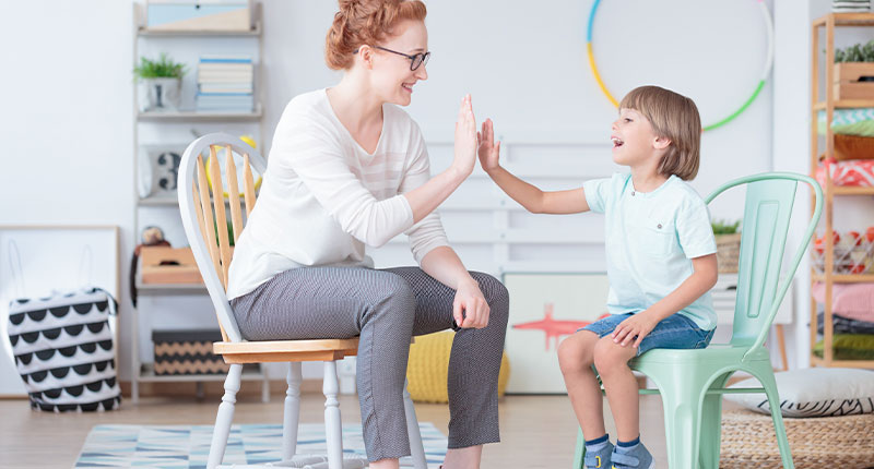 psicologa che da il cinque a un bambino felice